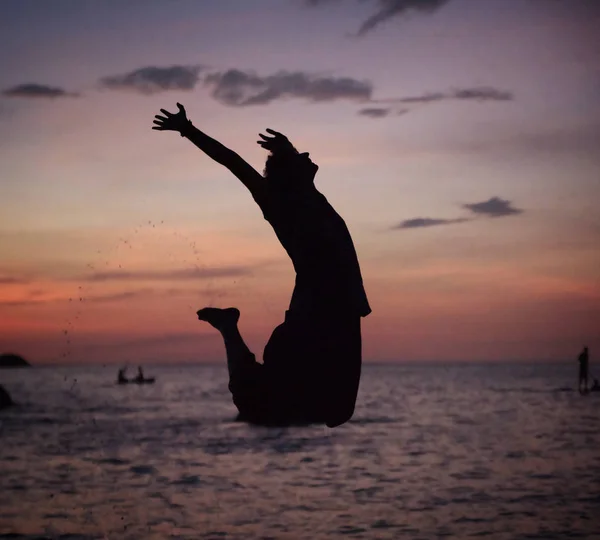 Silhouette eines entspannten Mannes, der am Strand springt — Stockfoto