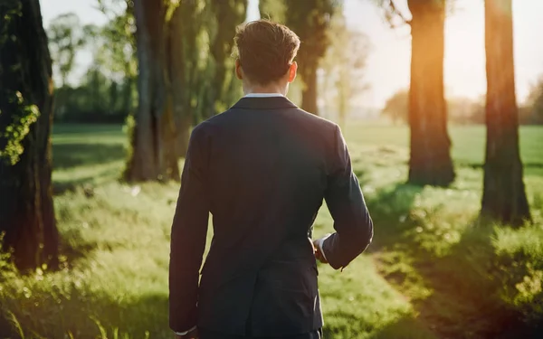 Young businessman walking among majestic, old trees — Stock Photo, Image