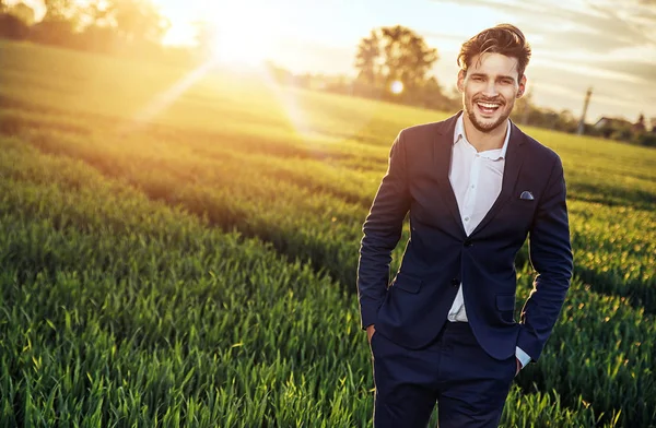 Optimistic businessman relaxing on the wheat field — Stock Photo, Image