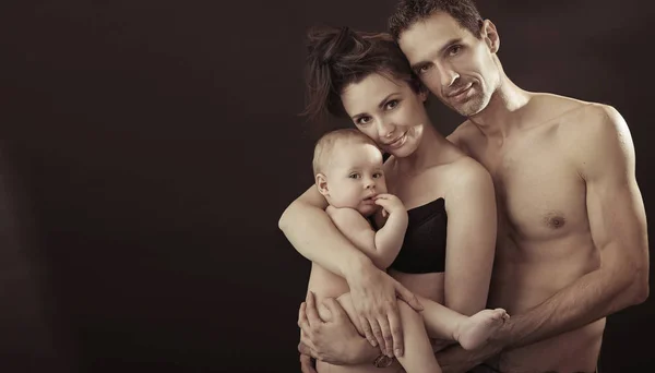 Familia feliz posando sobre fondo negro estudio —  Fotos de Stock