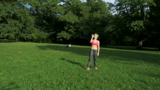 Подходит, молодая женщина растягивается в летнем парке — стоковое видео