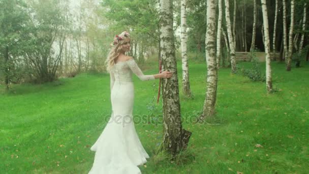 Delicate blond bride walking among trees — Stock Video