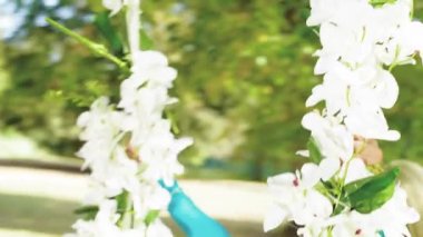 Çiçeklerden yapılmış bir salıncak üzerinde çekici sarışın