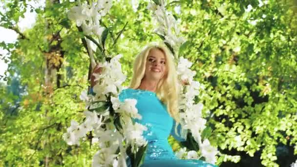 花的秋千上的迷人的金发碧眼 — 图库视频影像