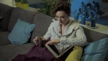 Geç akşam evde. Genç kadın bir kitap okuma