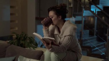 Geç akşam evde. Genç kadın bir kitap okuma