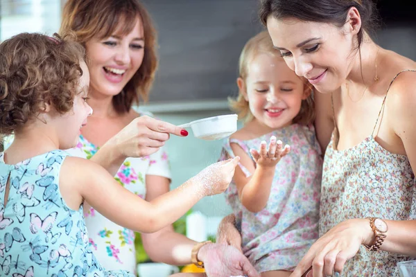 Две матери и их дочери пекут торт — стоковое фото