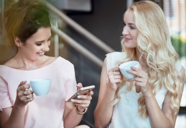 Kahve içme ve smartphone vasıl arıyorsunuz iki neşeli kadın