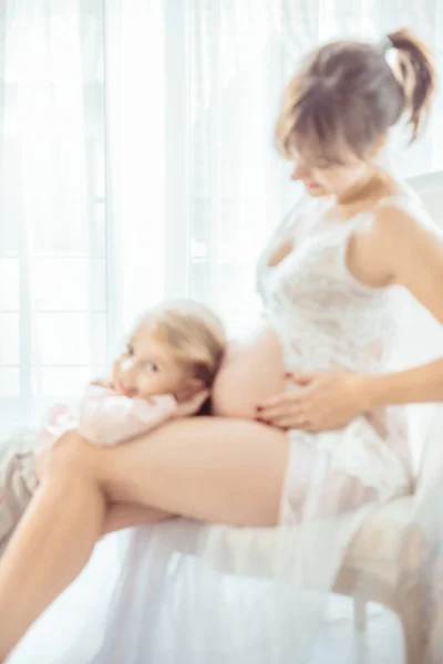 Charming daughter touching a pregnant mother's belly — Stock Photo, Image