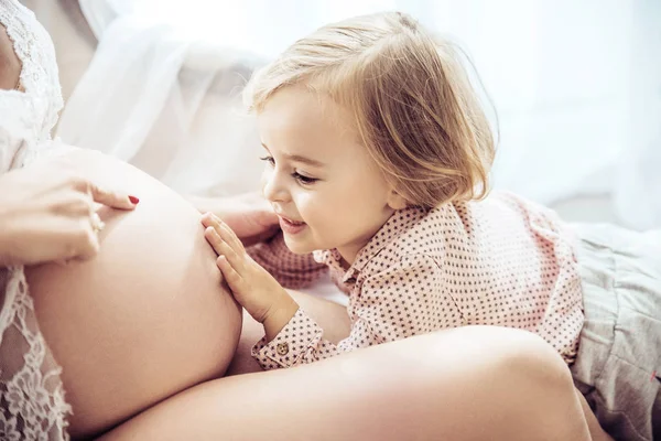 Charmante Tochter berührt den Bauch einer schwangeren Mutter — Stockfoto