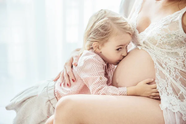 Bonito filhinha beijando a barriga de uma mãe — Fotografia de Stock