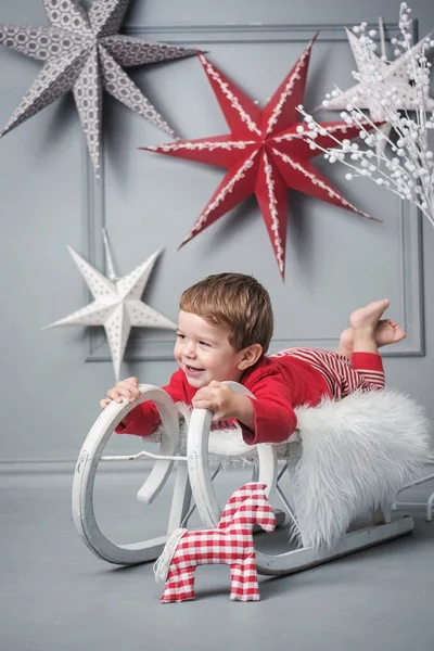 Cheerful kid laying on a christmas sleigh — Stock Photo, Image