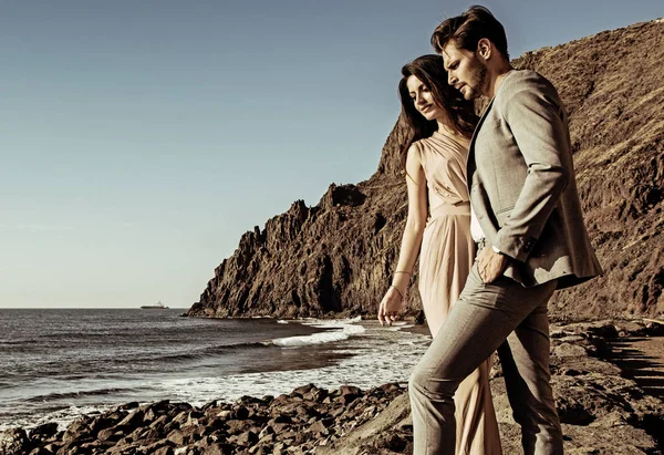 Portrait of an attractive couple looking at the ocean's wave — Stock Photo, Image