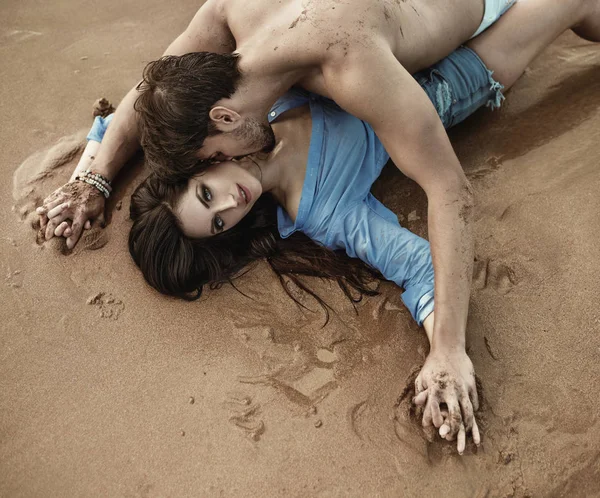 Portrait of a young sensual couple laying on the sand — Stock Photo, Image