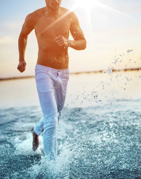 Foto de verano de un hombre corriendo por la orilla del mar Imagen de archivo