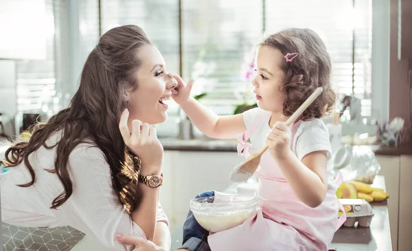 Mãe bonita e sua filha preparando um bolo — Fotografia de Stock