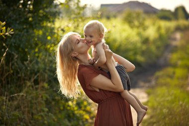 Güzel, genç bir anne sevgili oğlunu öpüyor.