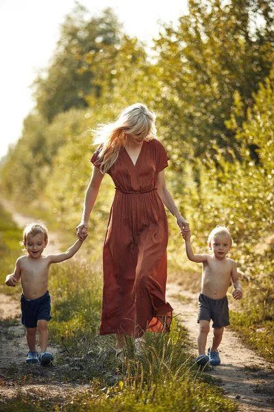 Веселая мать, гуляющая со своими двумя очаровательными сыновьями-близнецами — стоковое фото
