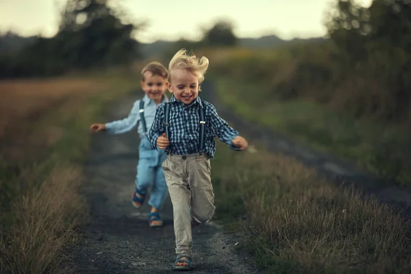 İki sevimli çocuk kır yolunda koşuyor. — Stok fotoğraf