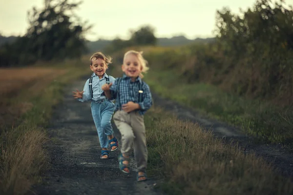 Dwóch uroczych chłopców biegających po wiejskiej drodze. — Zdjęcie stockowe