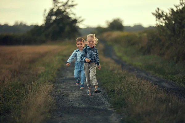 Dois meninos adoráveis correndo na estrada do campo — Fotografia de Stock