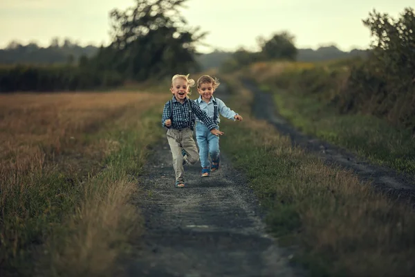 Två bedårande pojkar som springer på landsvägen Stockbild