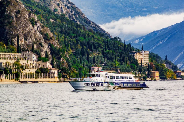 Limone Sul Garda, Brescia / Italy - 24 September 2017: Tourist boat floating on the lake Garda on background colorful houses, hotels and mountains.