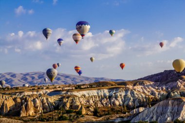 Goreme / Nevsehir, Türkiye - 27 Eylül 2019: Türkiye 'nin Kapadokya kentindeki vadi üzerinde uçan renkli sıcak hava balonları. Goreme Ulusal Parkı 'ndaki volkanik dağlar.