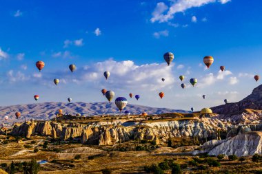 Goreme / Nevsehir, Türkiye - 27 Eylül 2019: Türkiye 'nin Kapadokya kentindeki vadi üzerinde uçan renkli sıcak hava balonları. Goreme Ulusal Parkı 'ndaki volkanik dağlar.