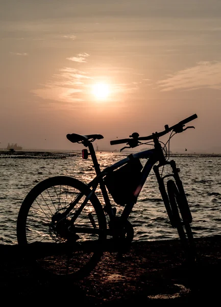 背景が夕焼け空の海でマウンテン バイクのシルエット — ストック写真