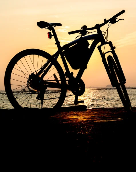 Silhueta de bicicleta de montanha no mar com fundo céu por do sol — Fotografia de Stock