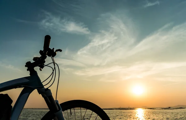 Berg fiets parkeren op zee en zonsondergang hemel achtergrond — Stockfoto