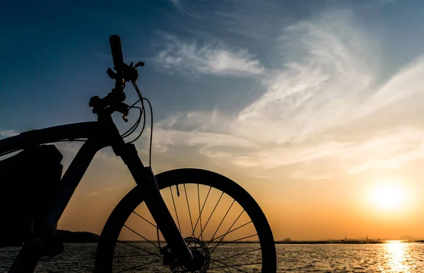 Berg fiets parkeren op zee en zonsondergang hemel achtergrond — Stockfoto