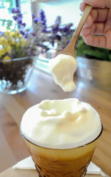 Milk foam from iced tea in spoon with woman hand — Stock Photo, Image