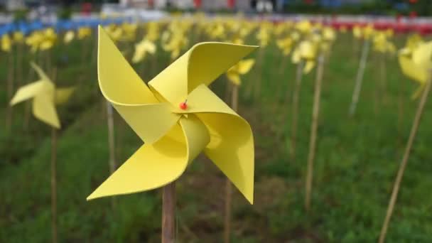 グリーン フィールド、ハンドヘルド撮影における風による回転黄色風車 — ストック動画