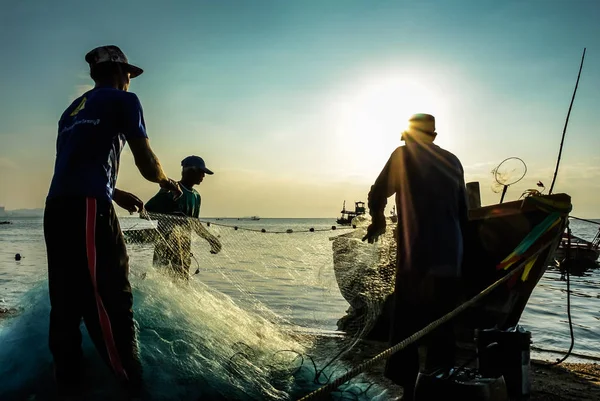 Group of fishermen clear fish from net — Stock Photo, Image