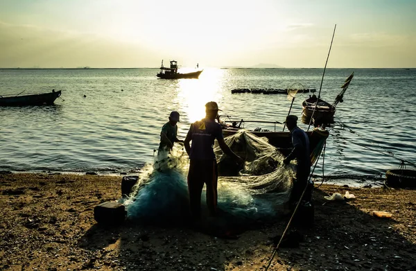 Группа рыбаков очищает рыбу от сети — стоковое фото