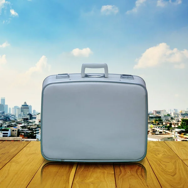 Vintage travel bag on wooden deck with cityscape background — Stock Photo, Image