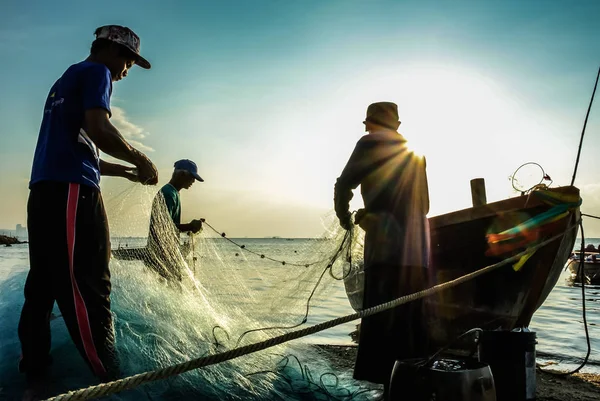 Group of fishermen clear fish from net — Stock Photo, Image