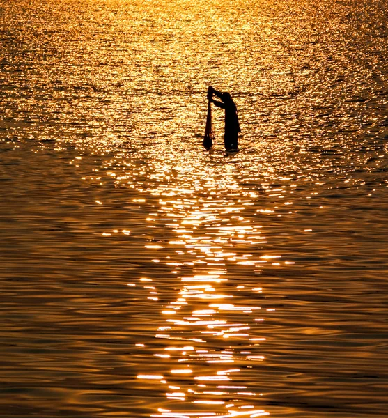 Fisherman with net in sea with sunset light reflection on sea wa — Stock Photo, Image