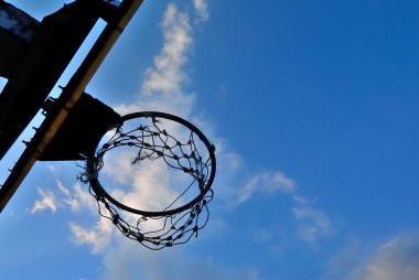 Basketbol potası silueti ve mavi gökyüzünde bulutlar.