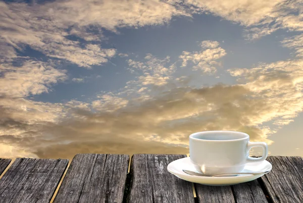 Filiżanka kawy na drewnianym stole z porannym tle nieba — Zdjęcie stockowe