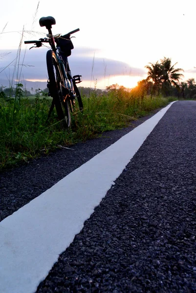 Parcheggio mountain bike accanto alla linea stradale con zaino cielo mattina — Foto Stock