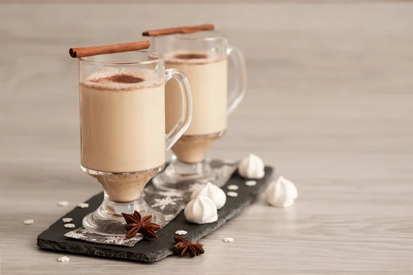 Eggnog in glass cups with a delicate foam, spices and a cinnamon stick — ストック写真