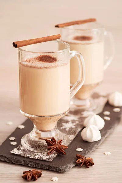 Eggnog in glass cups with a delicate foam, spices and a cinnamon stick — ストック写真