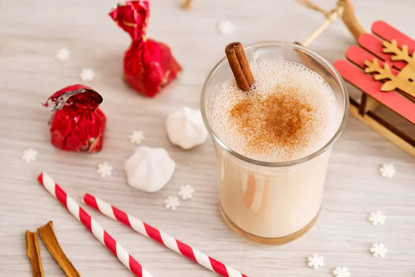 Eggnog in glass cups with a delicate foam, spices and a cinnamon stick — ストック写真