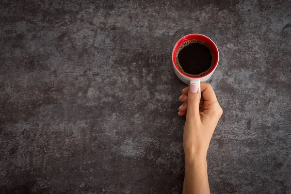 Tangan wanita memegang cangkir kopi di atas meja gelap — Stok Foto