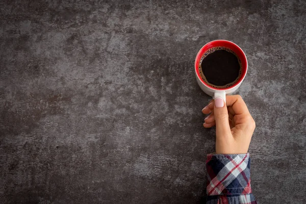 Tangan wanita memegang cangkir kopi di atas meja gelap — Stok Foto