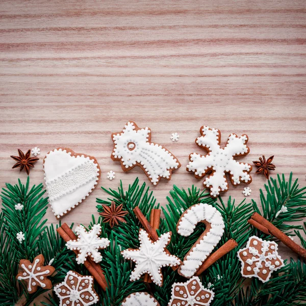 Frame met dennentakken, koekjes en kerstversieringen op een houten ondergrond. Bovenaanzicht. — Stockfoto