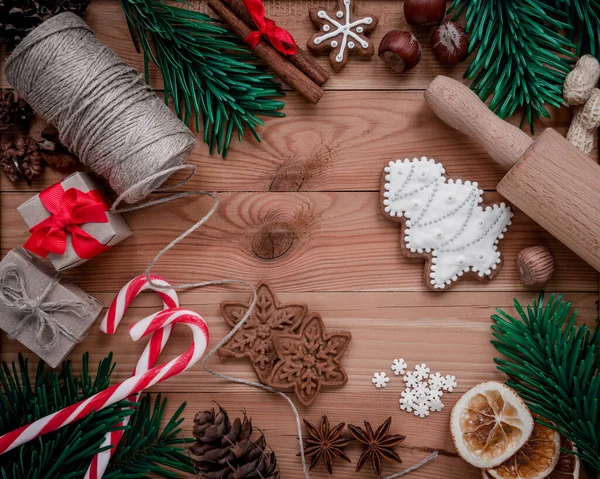 Ahşap arka planda köknar dalları, kurabiyeler ve Noel süslemeleri olan çerçeve. Üst görünüm. — Stok fotoğraf